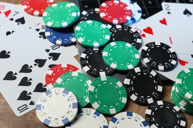 Photo of Poker chips, laptop and playing cards on wooden table, closeup. Online game