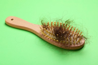 Photo of One brush with lost hair on light green background. Alopecia problem