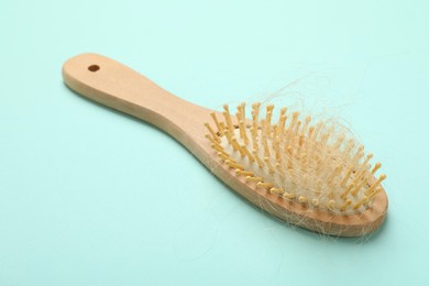 One brush with lost hair on light blue background. Alopecia problem