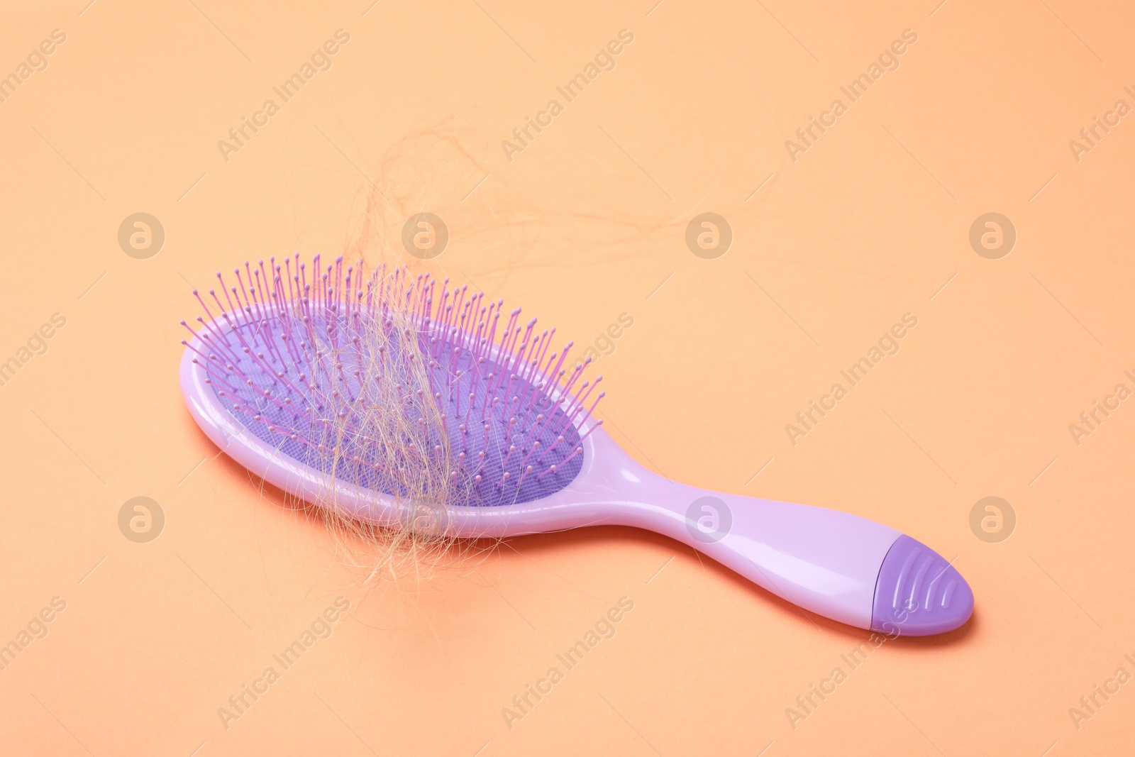 Photo of One brush with lost hair on coral background. Alopecia problem