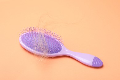 Photo of One brush with lost hair on coral background. Alopecia problem