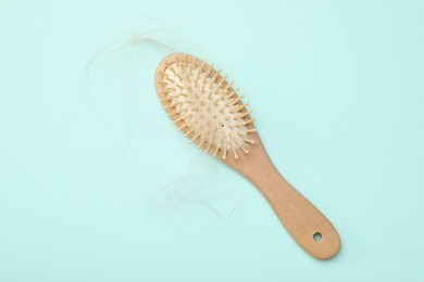 One brush with lost hair on light blue background, top view. Alopecia problem