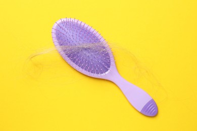 Photo of One brush with lost hair on yellow background, top view. Alopecia problem