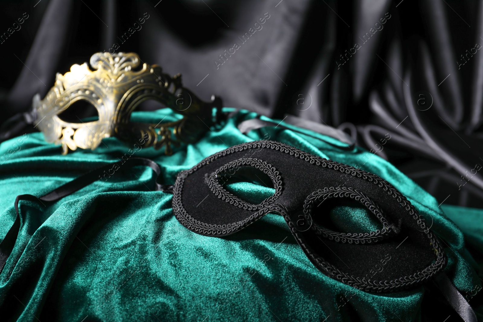 Photo of Beautiful carnival masks on silk fabric, closeup