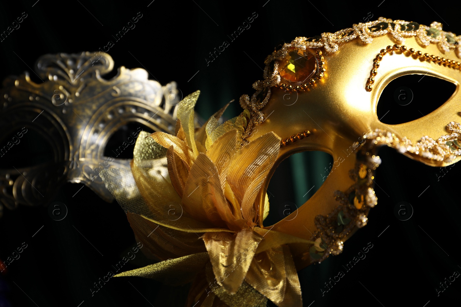 Photo of Beautiful carnival masks in darkness, closeup view