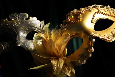 Photo of Beautiful carnival masks in darkness, closeup view