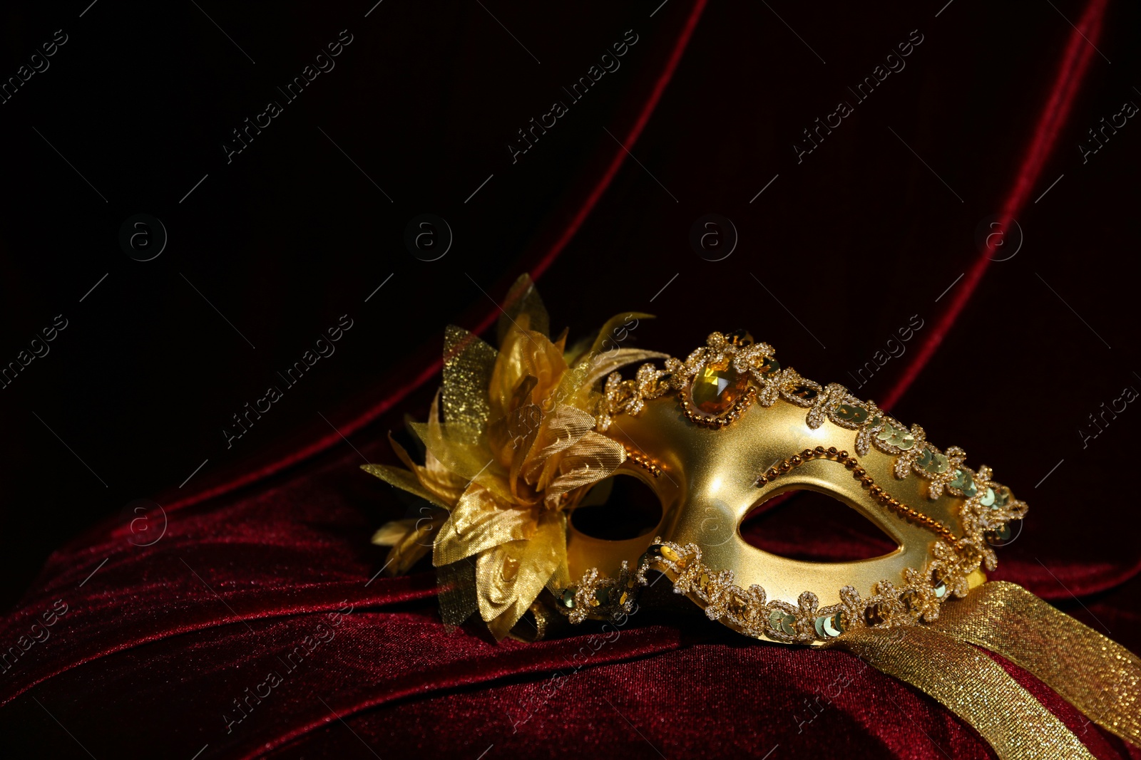 Photo of Beautiful golden carnival mask on red silk fabric