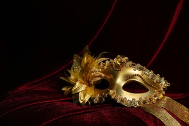 Photo of Beautiful golden carnival mask on red silk fabric