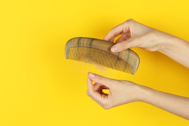 Photo of Woman taking lost hair from comb on yellow background, closeup. Space for text