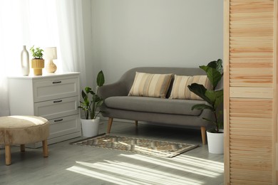 Photo of Wooden folding screen, sofa and houseplants in living room