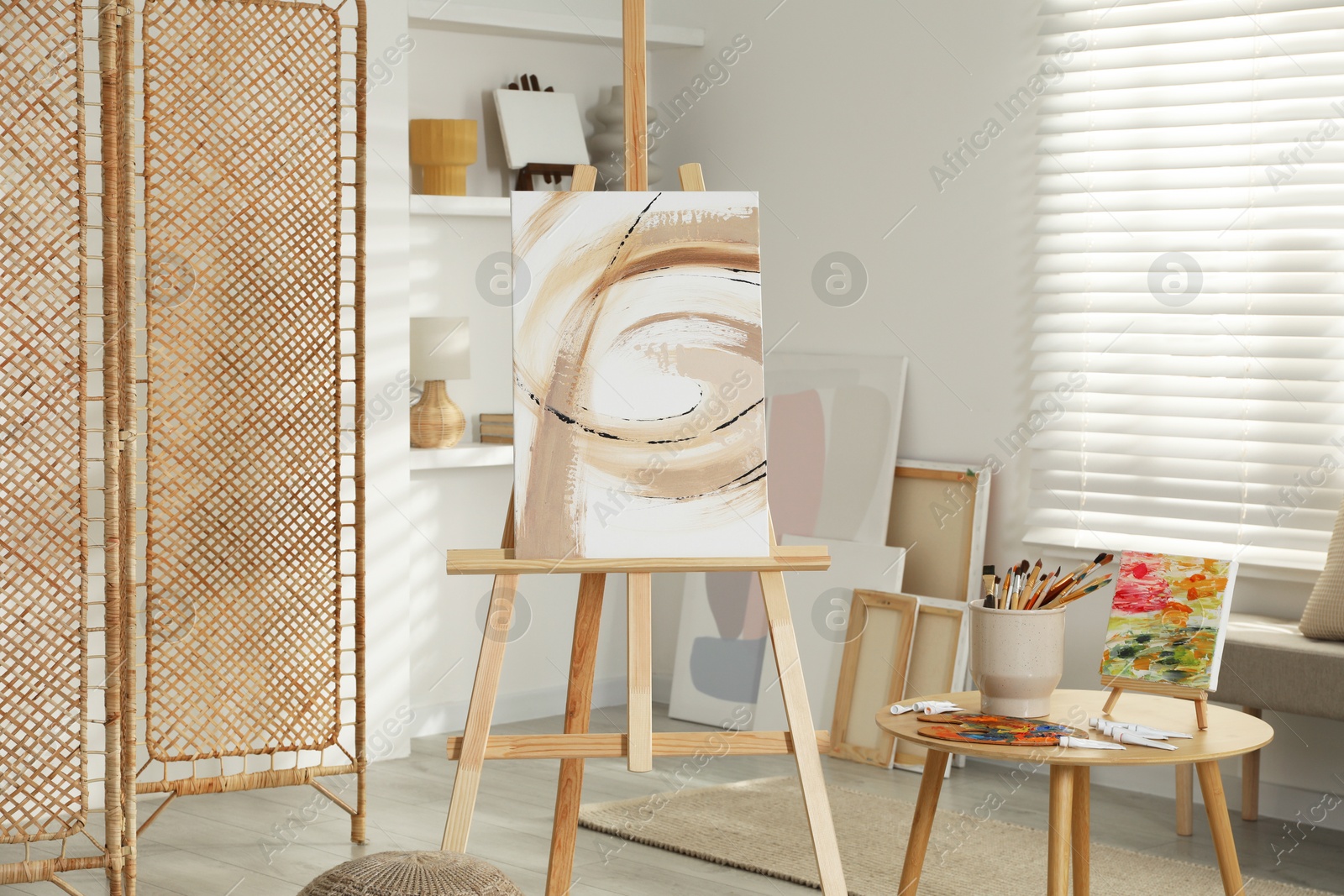 Photo of Folding screen and easels with beautiful abstract paintings in room