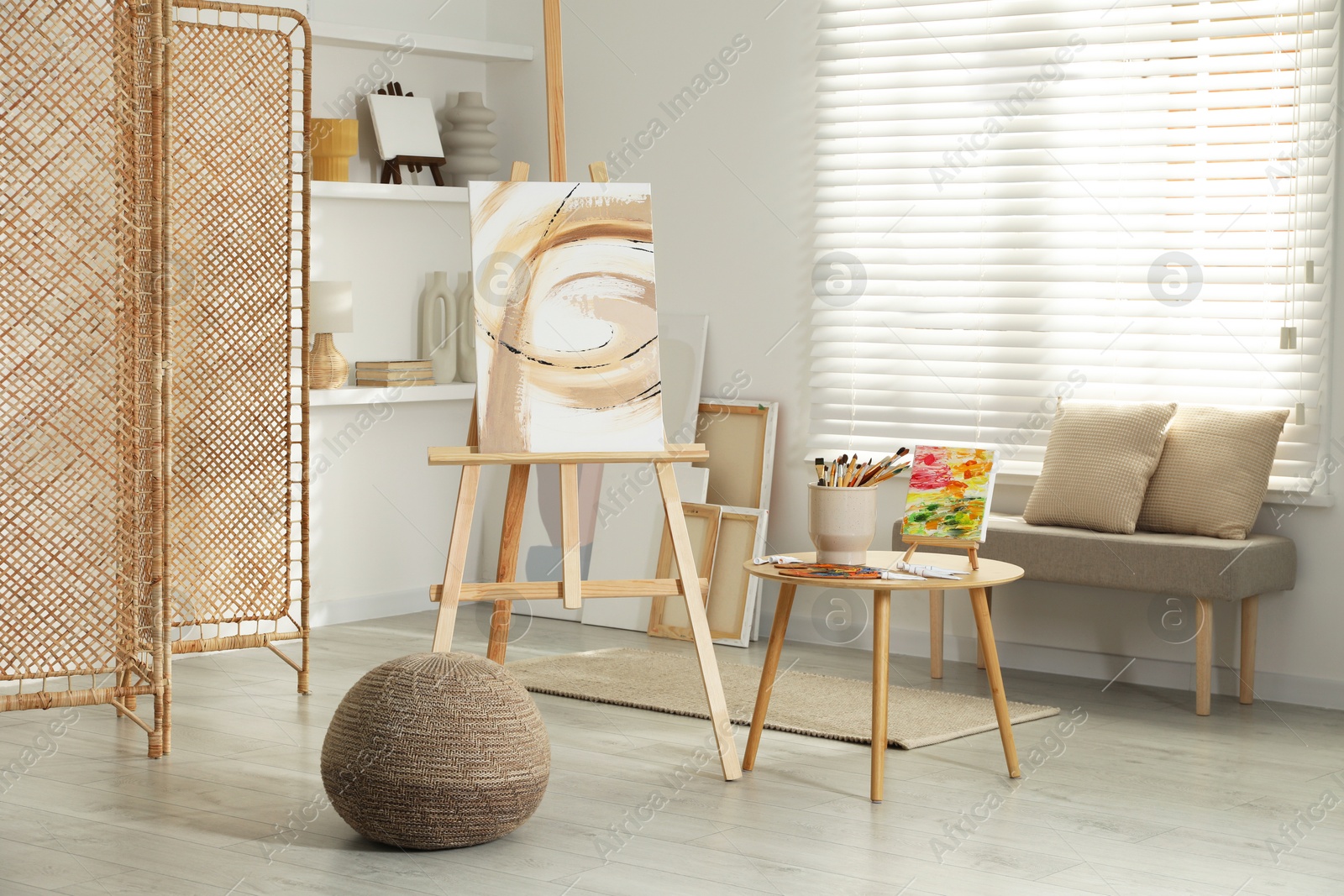 Photo of Folding screen and easels with beautiful abstract paintings in room