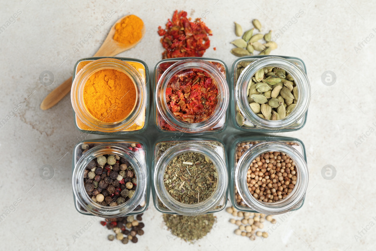 Photo of Different spices in glass jars on light grey table, top view