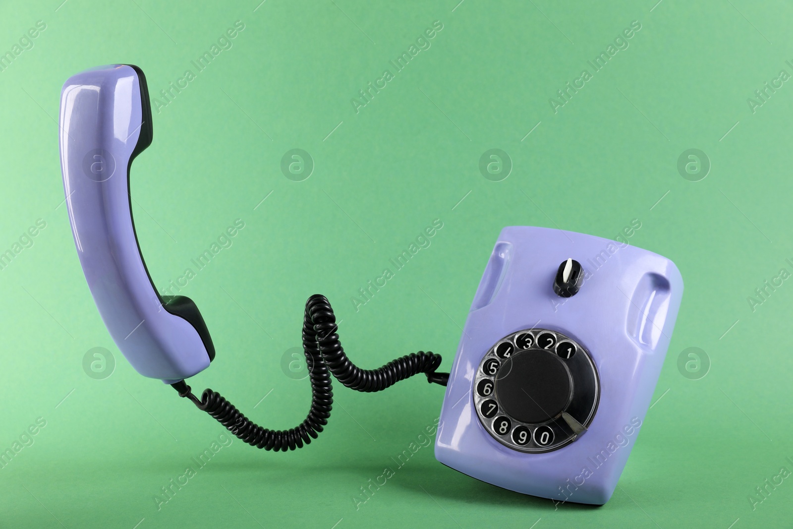 Photo of One violet telephone with handset on green background