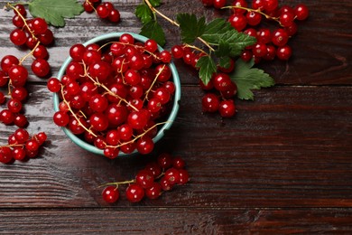 Fresh red currants and green leaves on wooden table, top view. Space for text