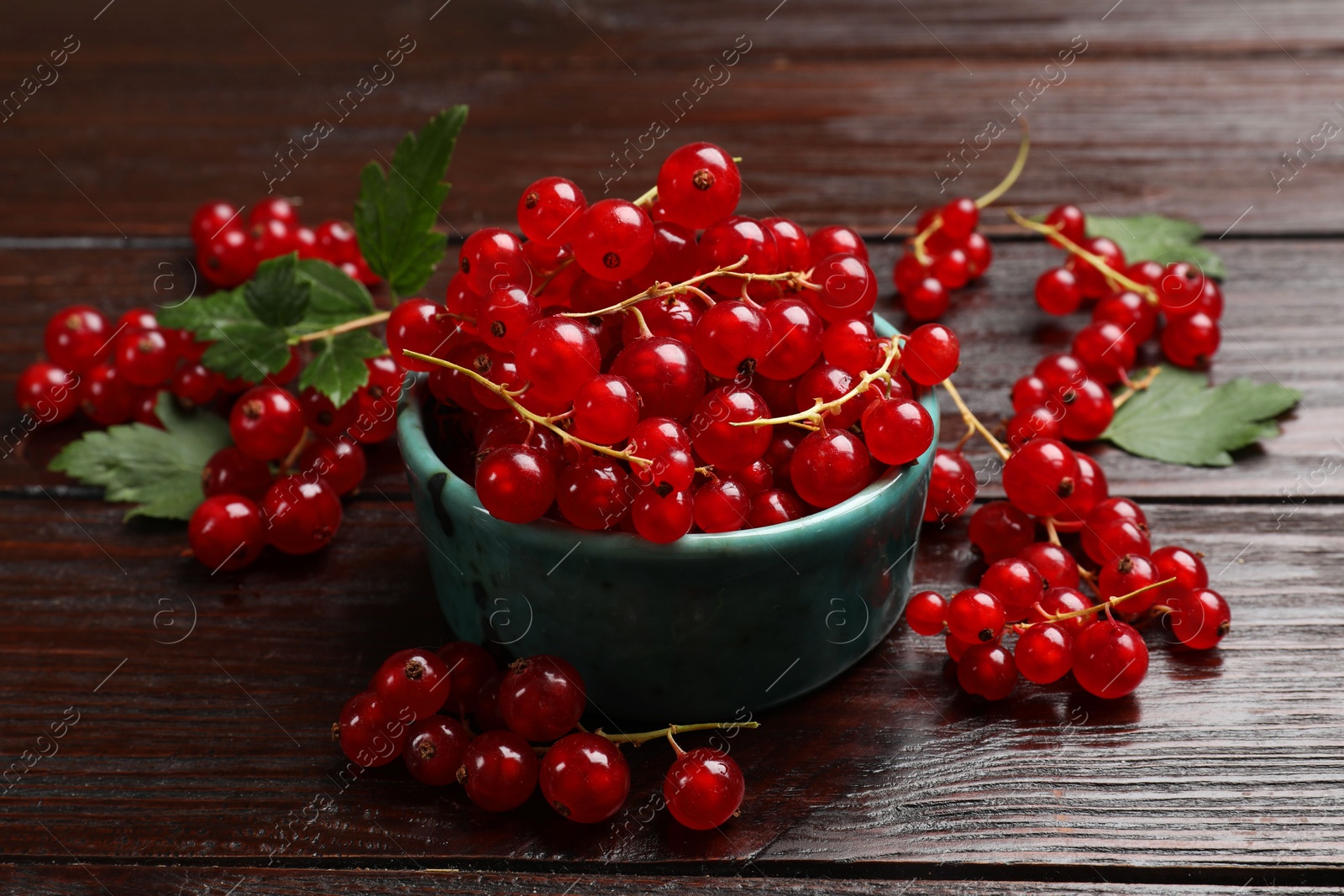 Photo of Fresh red currants and green leaves on wooden table, closeup