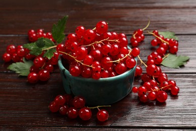 Fresh red currants and green leaves on wooden table, closeup