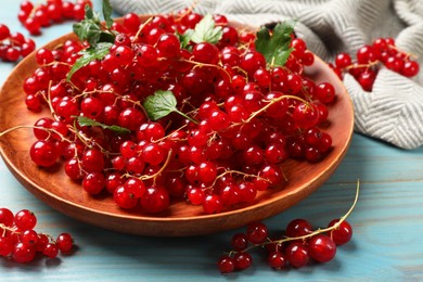 Fresh red currants and leaves on light blue wooden table, closeup