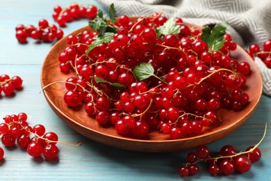 Fresh red currants and leaves on light blue wooden table, closeup