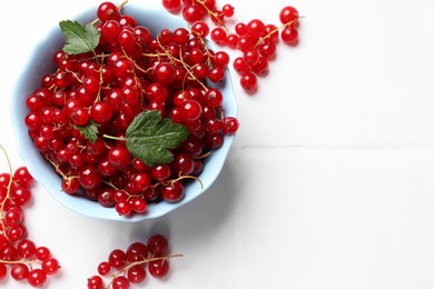 Photo of Fresh red currants in bowl on white table, top view. Space for text