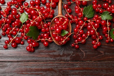 Photo of Fresh red currants and green leaves on wooden table, top view. Space for text