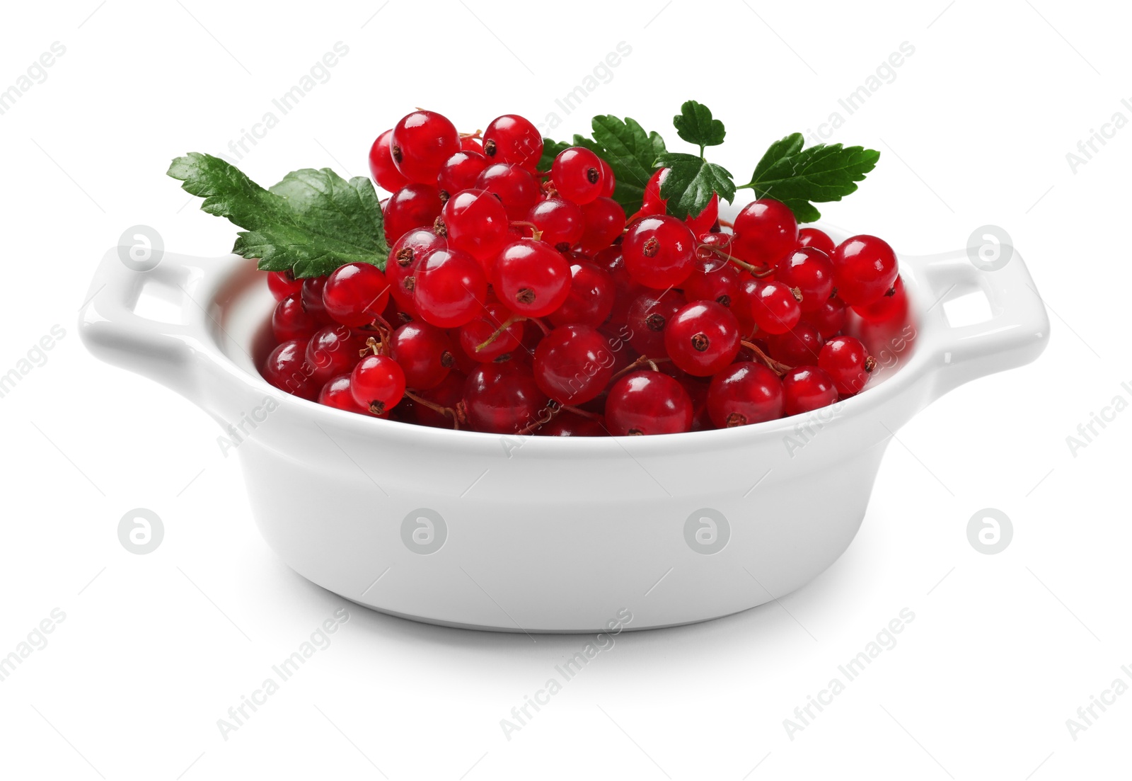 Photo of Ripe red currants with green leaves in bowl isolated on white