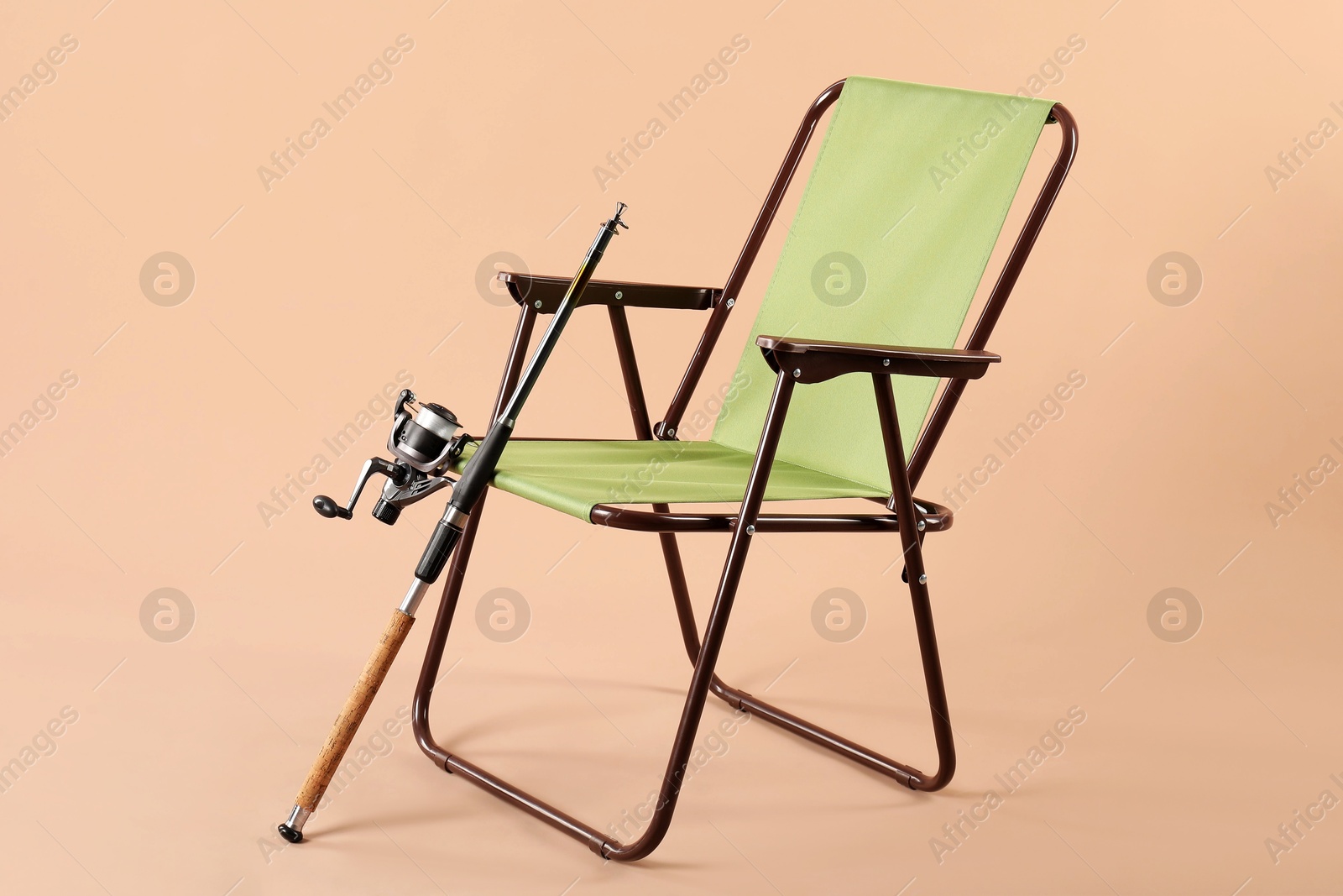 Photo of Folding chair and fishing rod on beige background