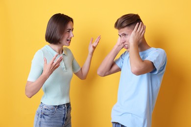 Emotional young couple arguing on orange background