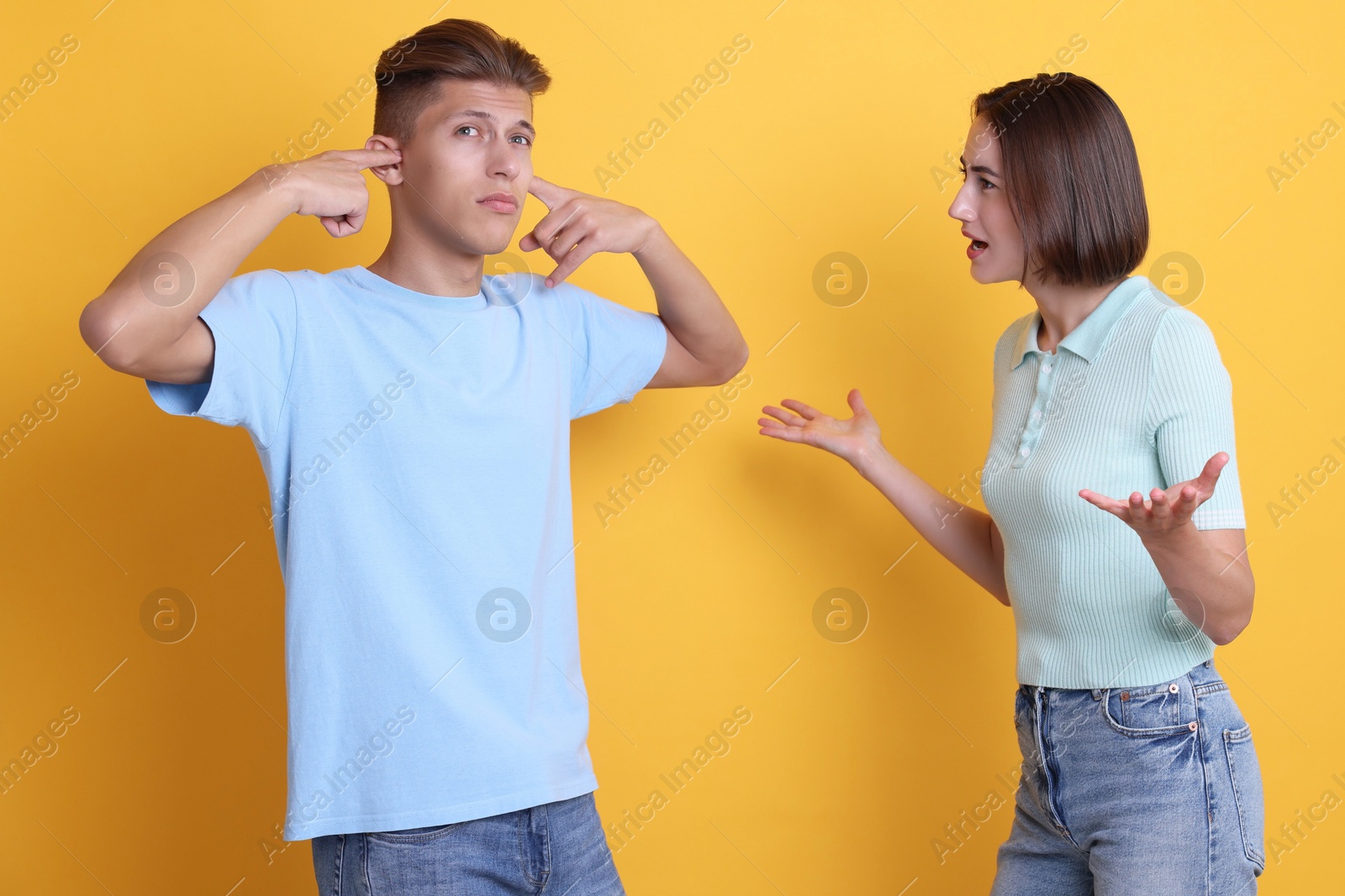 Photo of Emotional young couple arguing on orange background