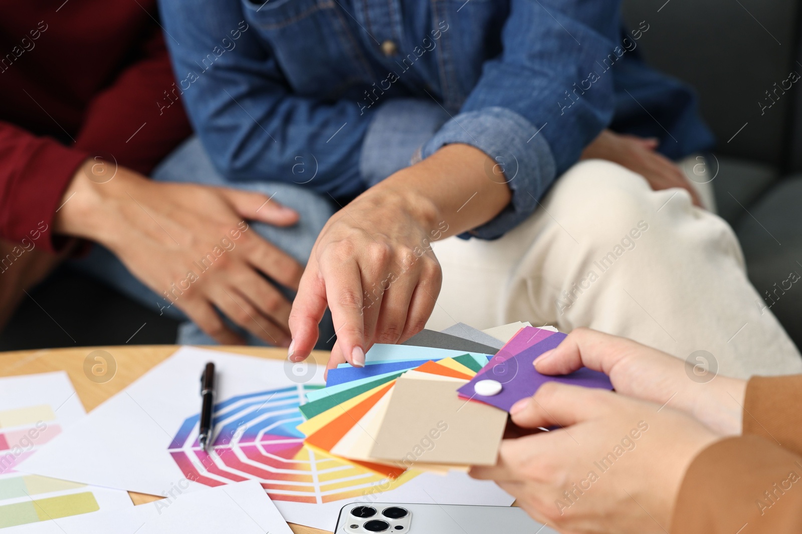 Photo of Designer discussing project with clients at table indoors, closeup