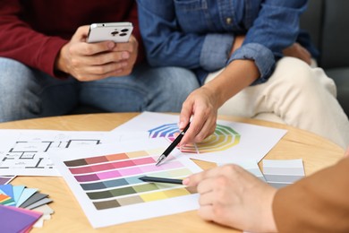 Photo of Designer discussing project with clients at table indoors, closeup