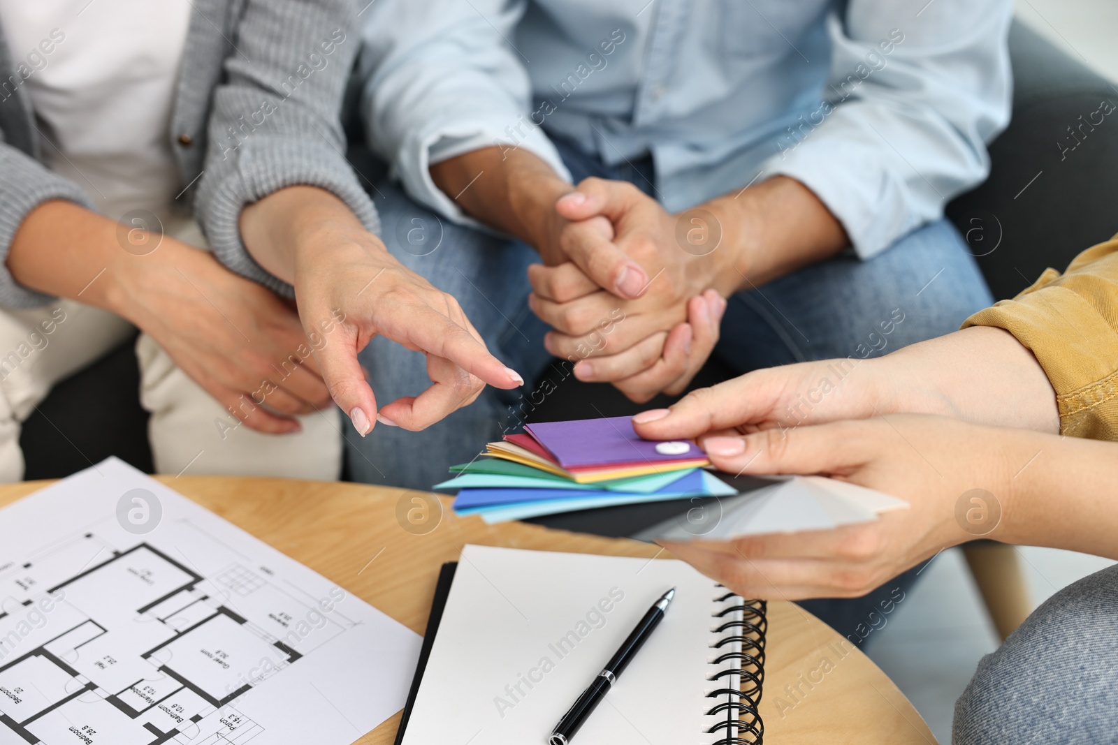 Photo of Designer discussing project with clients at table indoors, closeup