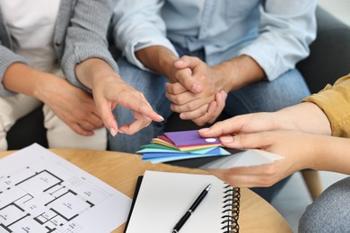 Designer discussing project with clients at table indoors, closeup