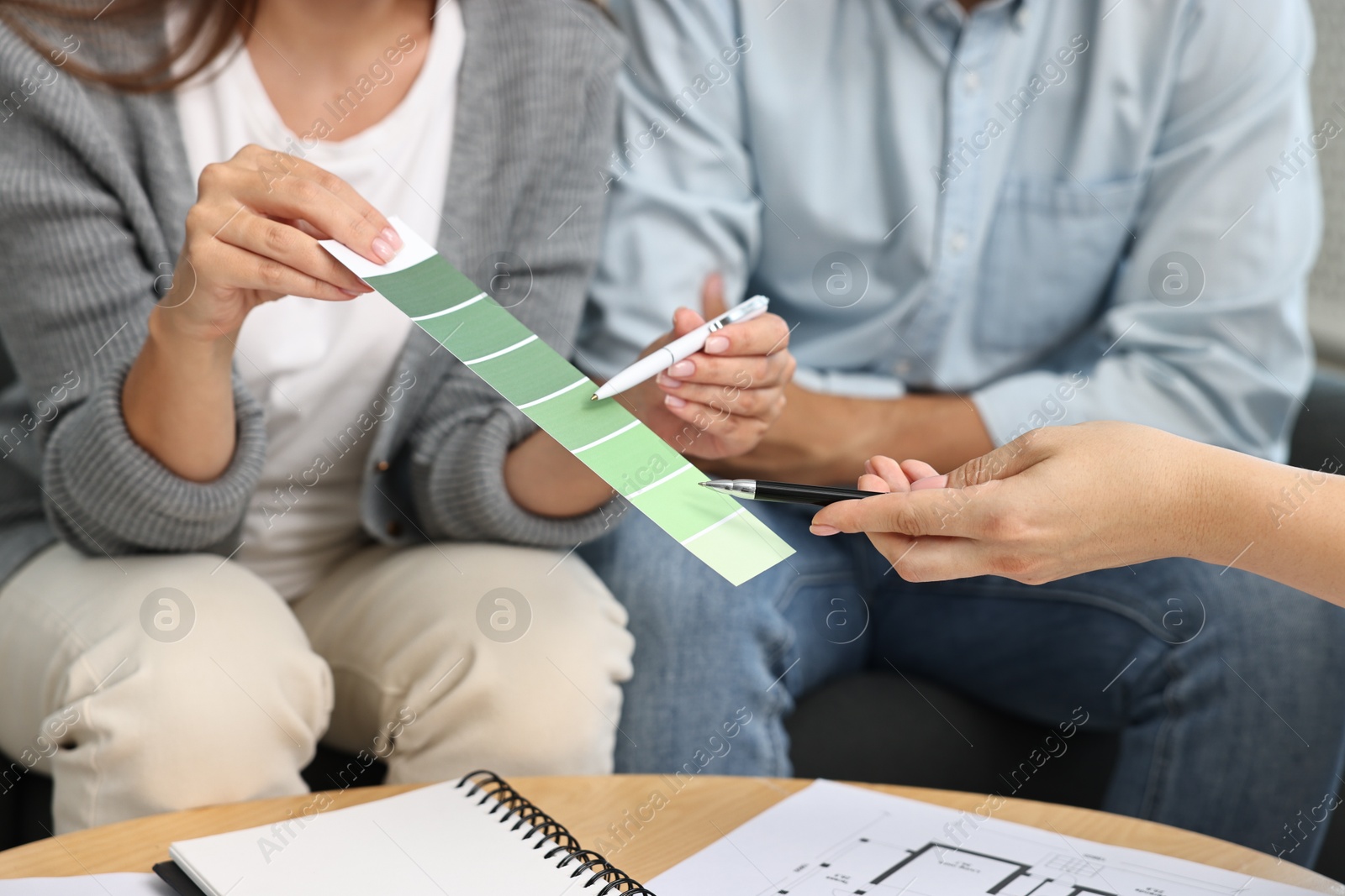 Photo of Designer discussing project with clients at table indoors, closeup