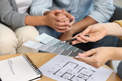 Designer discussing project with clients at table indoors, closeup