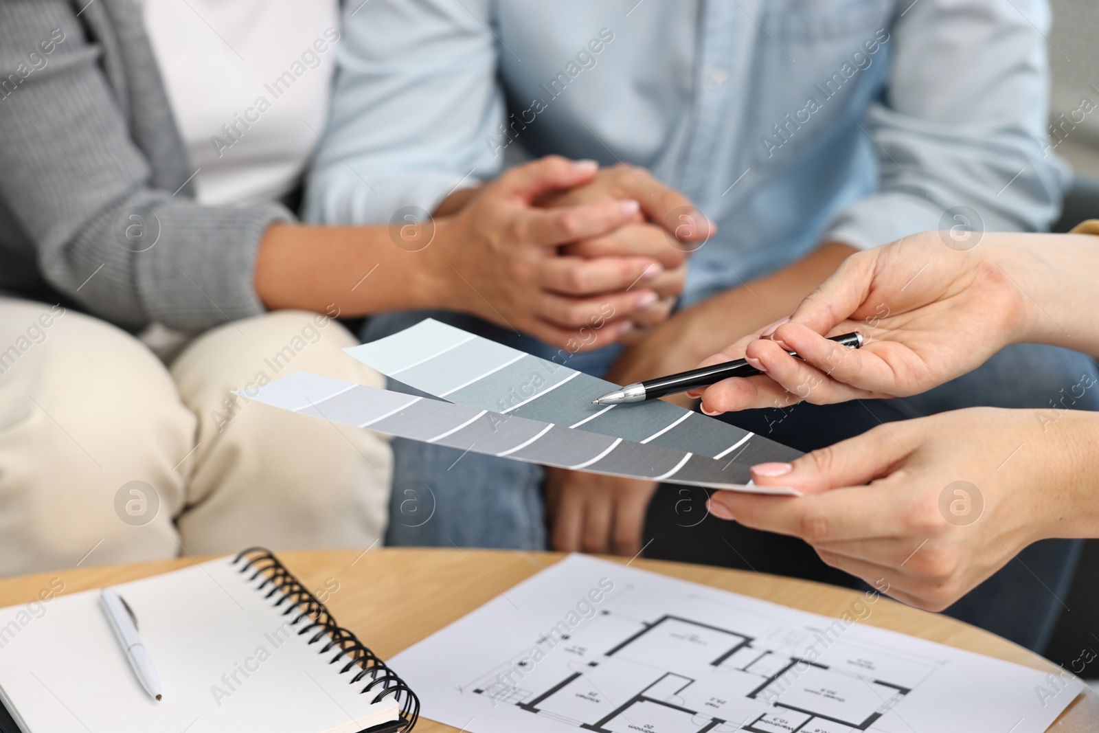 Photo of Designer discussing project with clients at table indoors, closeup