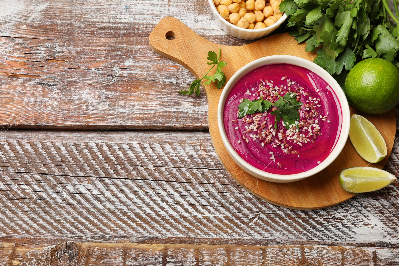 Photo of Tasty beetroot hummus in bowl and products on wooden table, flat lay. Space for text