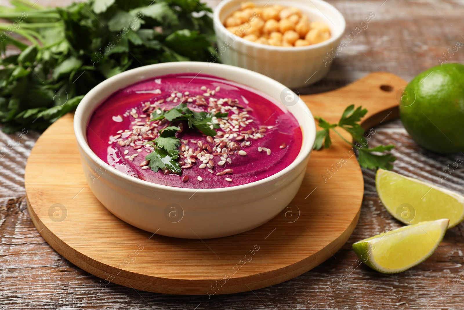 Photo of Tasty beetroot hummus in bowl and products on wooden table