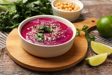 Photo of Tasty beetroot hummus in bowl and products on wooden table