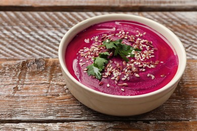 Photo of Tasty beetroot hummus, parsley and seeds in bowl on wooden table, closeup. Space for text