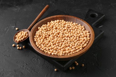 Photo of Dried peas in bowl and spoon on dark textured table, closeup