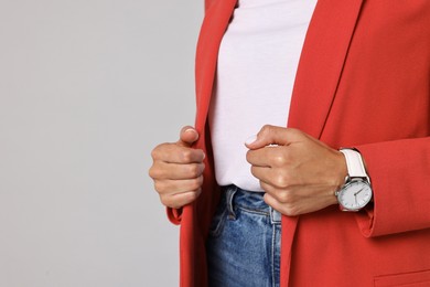 Woman in red jacket on gray background, closeup. Space for text