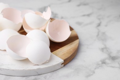 Photo of Broken eggshells on light marble table, closeup. Space for text