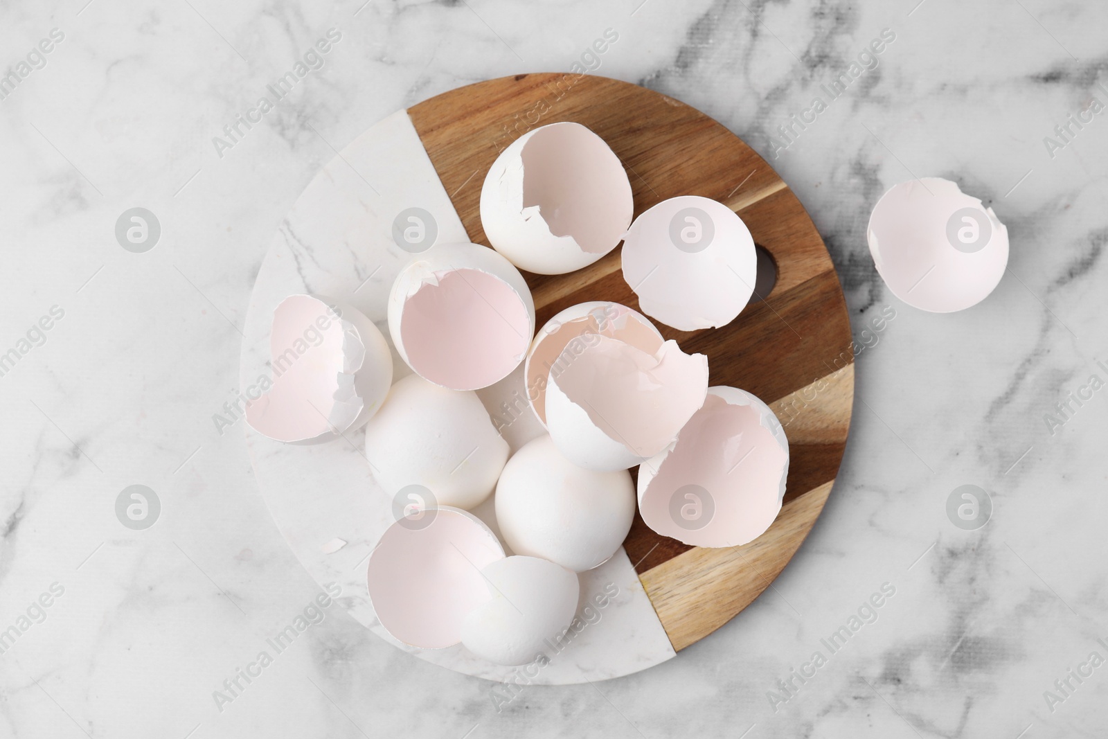 Photo of Broken eggshells on light marble table, top view