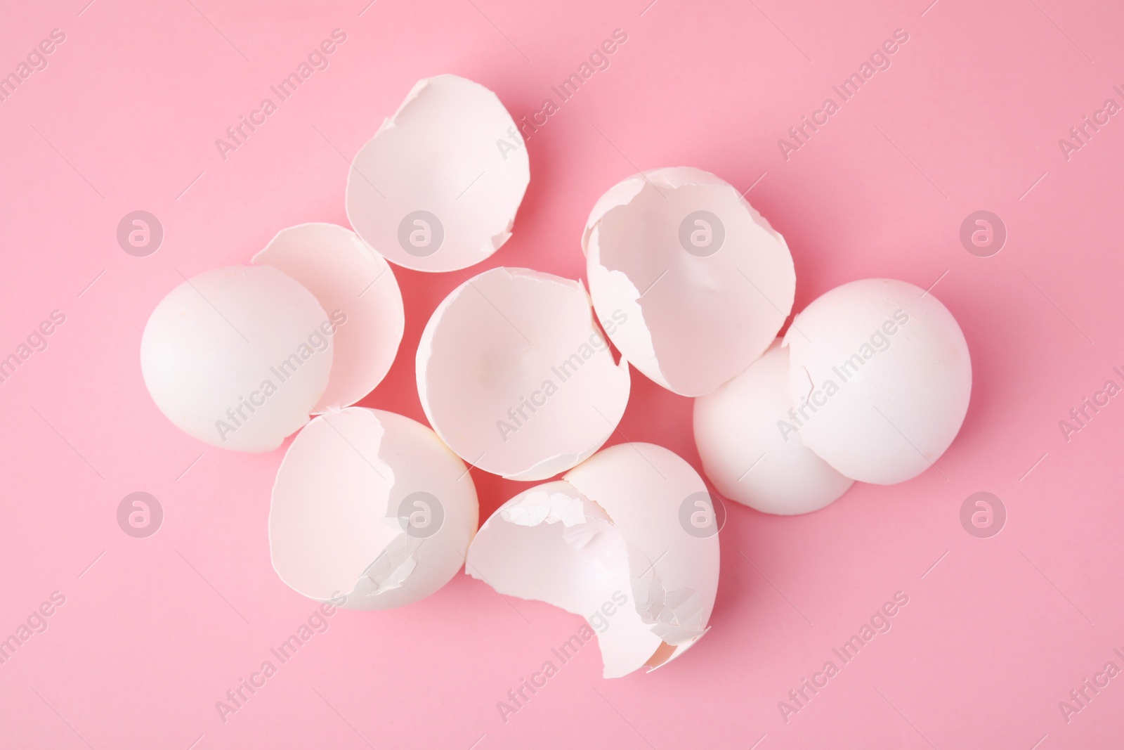 Photo of Broken eggshells on pink background, top view