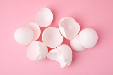 Photo of Broken eggshells on pink background, top view