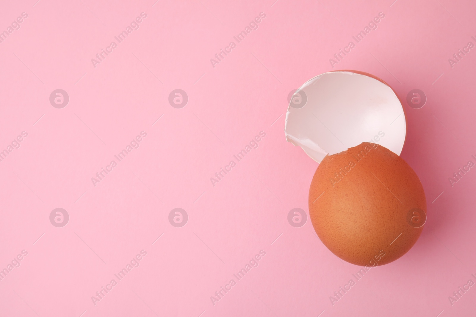 Photo of Pieces of broken eggshells on pink background, top view. Space for text