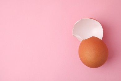 Photo of Pieces of broken eggshells on pink background, top view. Space for text