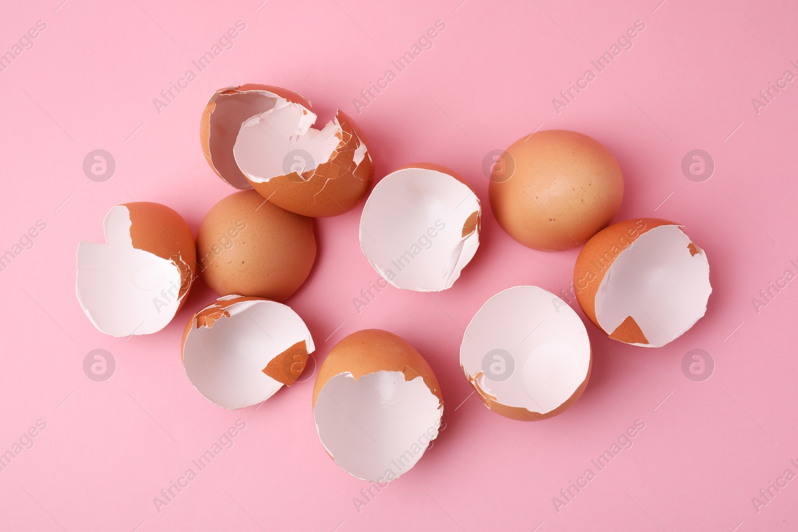 Photo of Broken eggshells on pink background, top view