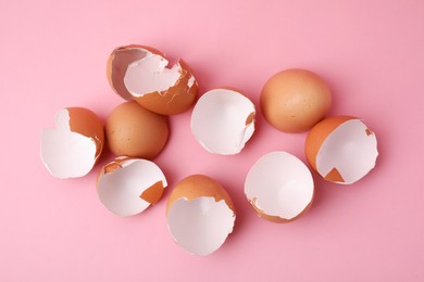 Photo of Broken eggshells on pink background, top view